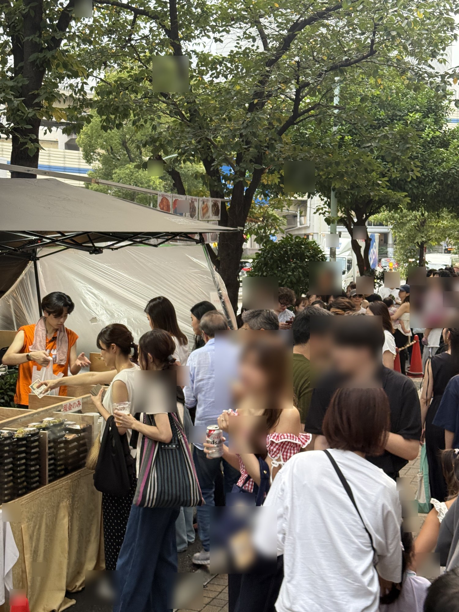 富麗華の店舗表側にできた長い行列と、オレンジのスタッフウェアで販売するスタッフ
