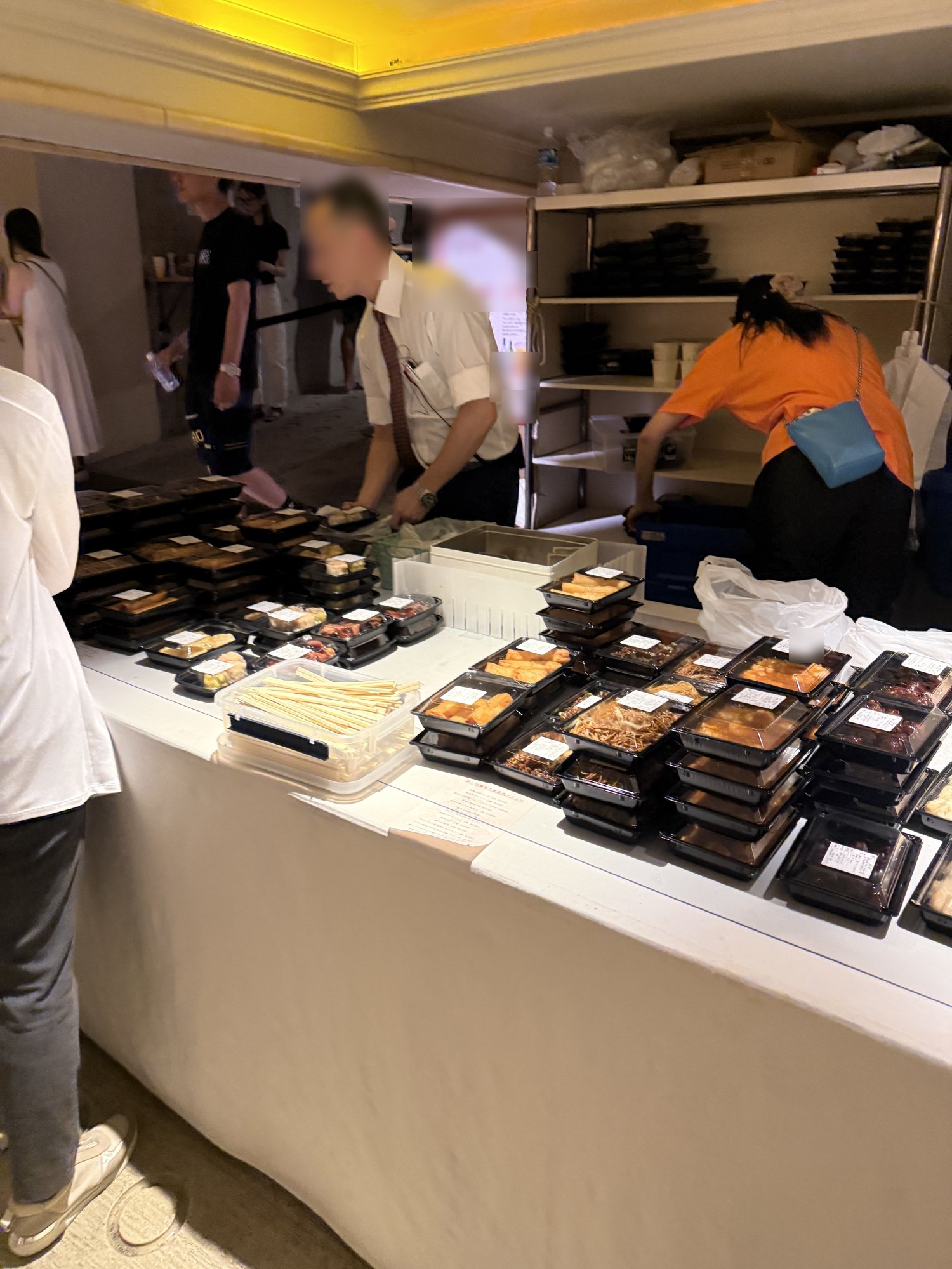地下駐車場内の販売コーナー。スタッフが料理をパックに詰めている様子