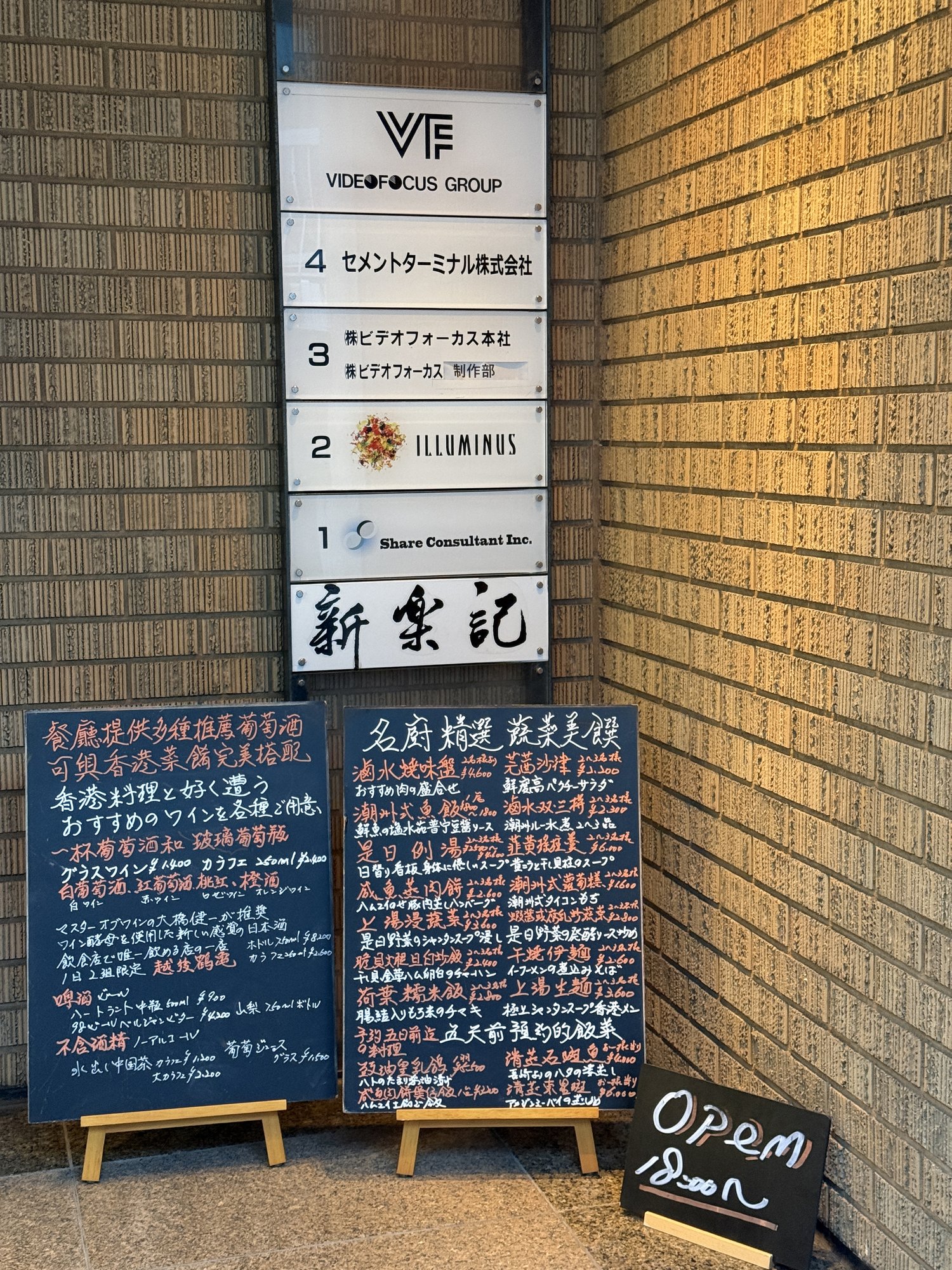 新楽記が入るビデオフォーカスビルの入居案内板と、店頭に置かれた黒板メニュー
