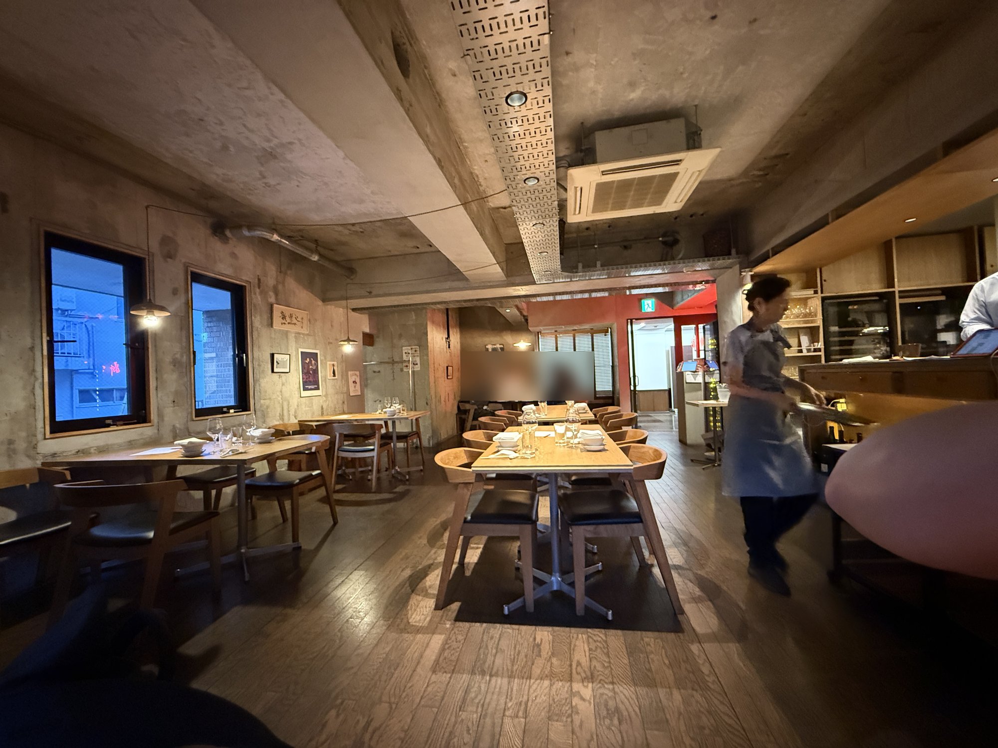 新楽記の店内。コンクリートの天井と木のテーブルが並ぶ落ち着いたダイニングスペース