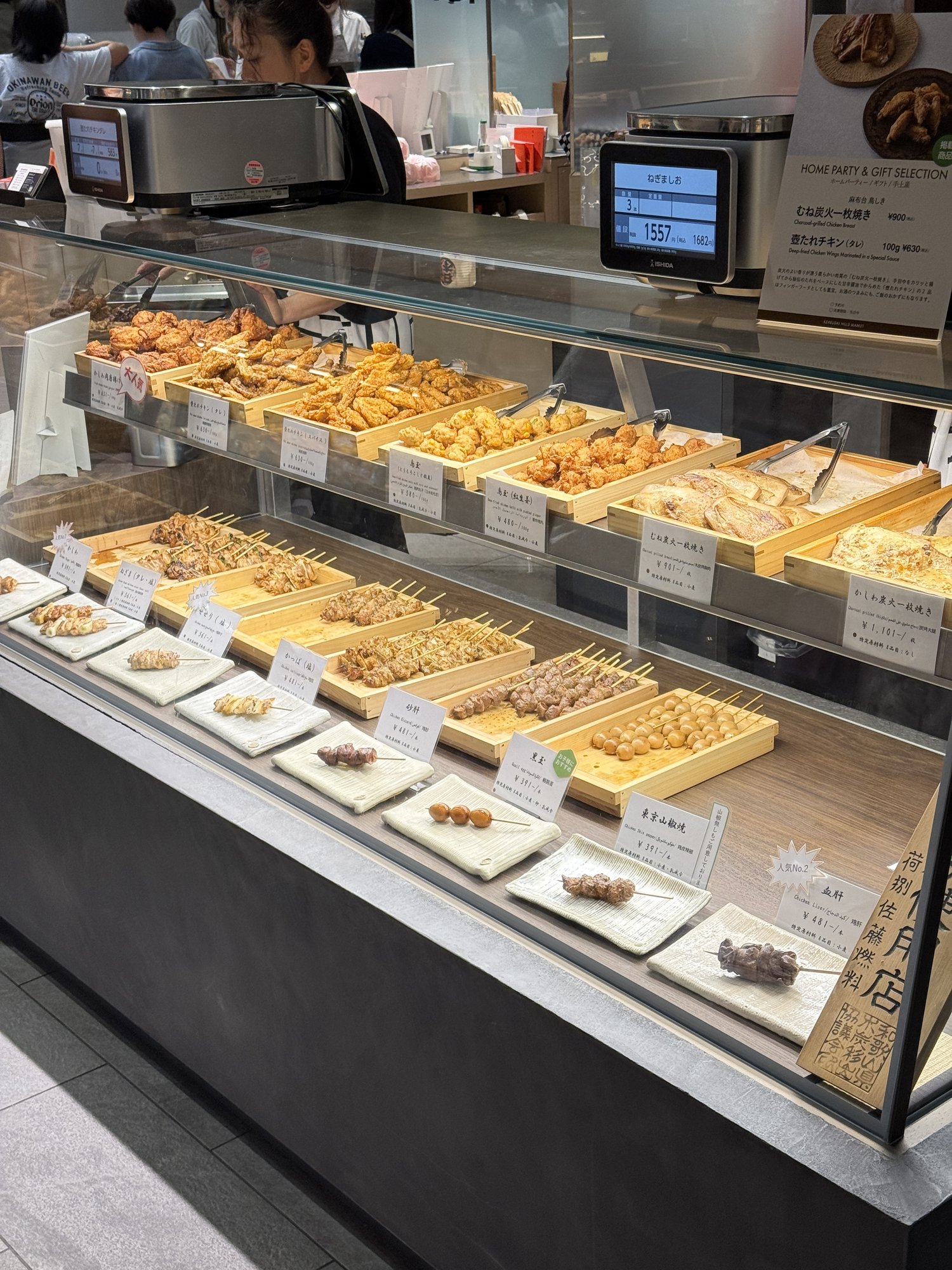 麻布台鳥しきのショーケースに並ぶ焼き鳥の串と、値札が付いた商品の数々
