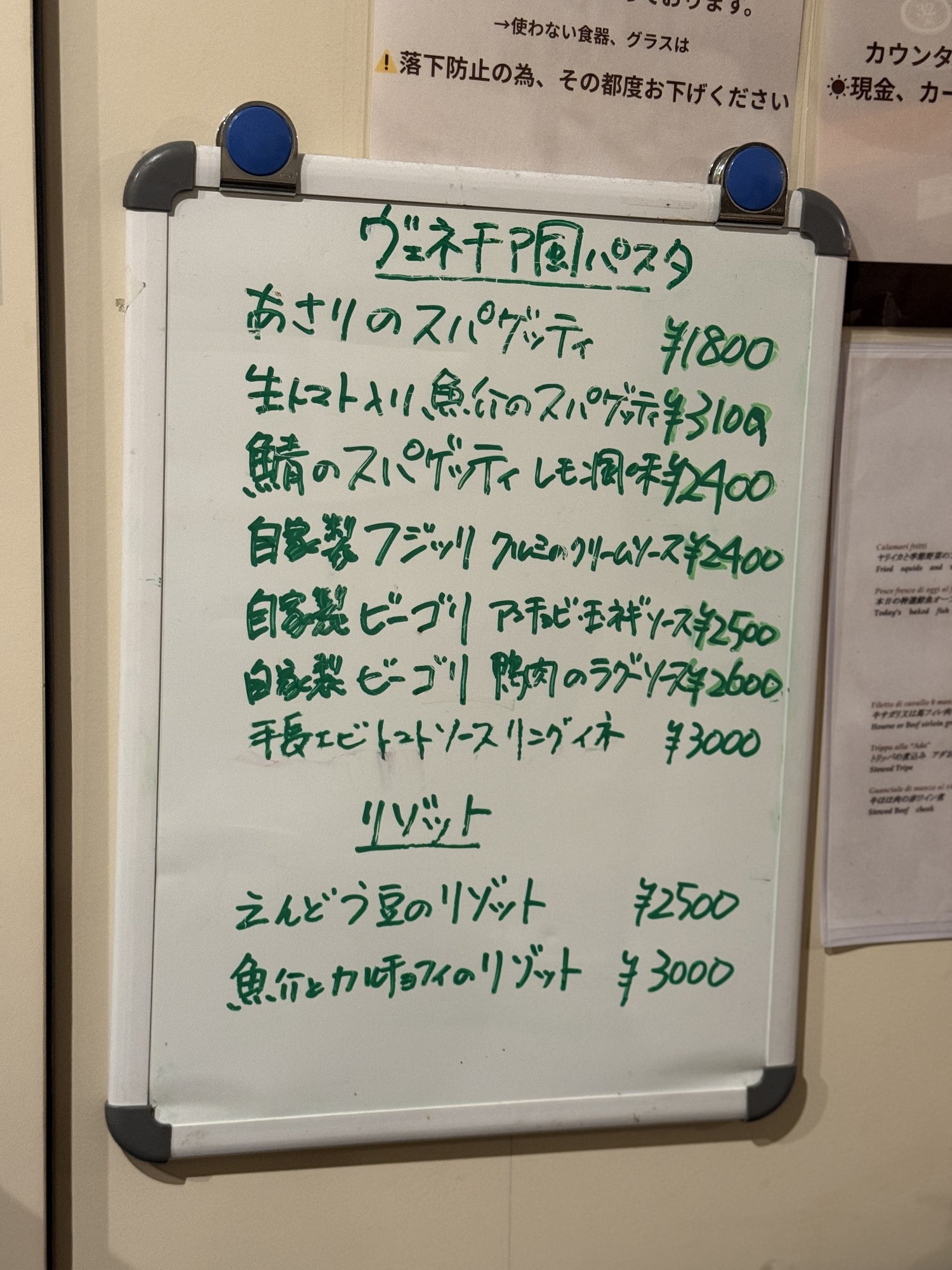ホワイトボードに手書きされたパスタとリゾットのメニューと価格